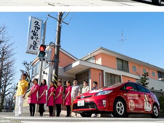職員が並ぶ施設外観  