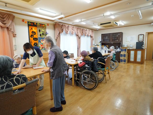 活動的な食堂風景 共有スペース 明るく広々とした食堂で、利用者が様々な活動に取り組む姿が見られます。スタッフと利用者が一緒に時間を過ごしており、笑顔も交わされています。