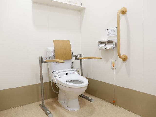 バリアフリーのトイレ 介護用トイレてすりと緊急ボタン 安全に配慮された手すり付きトイレです。快適さと利便性を兼ね備え、全員が使いやすい環境を提供しています。