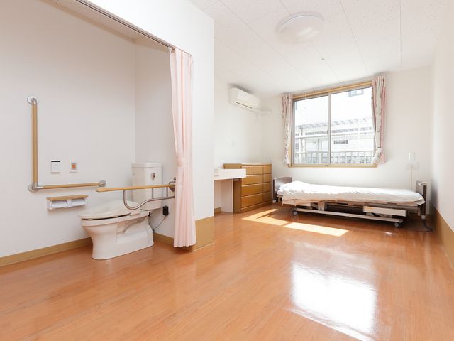 居室の清潔な様子 洋室 広々とした明るい居室です。手すり付きトイレや高さ調節可能なベッドが整っており、快適な利用を支援しています。