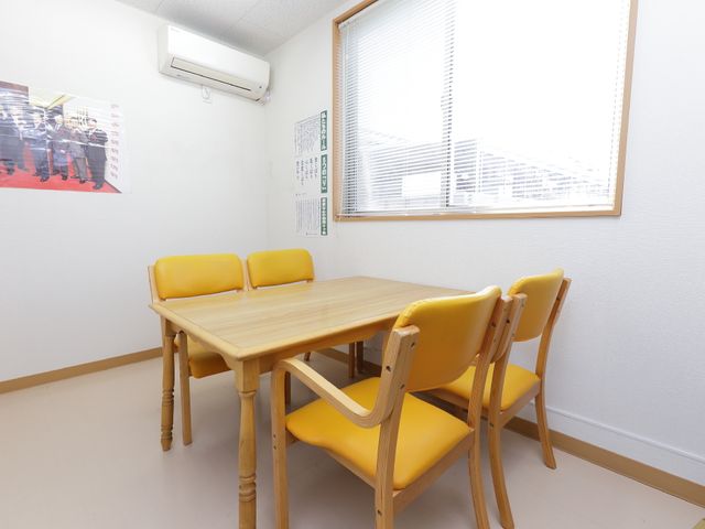 居室のテーブルと椅子 談話室 明るく落ち着いた雰囲気の居室です。ゆったりとした時間を過ごすことができるスペースが整っています。