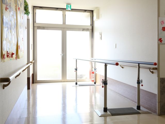 廊下に設けられた手すり 通路 手すりが廊下に備え付けられており、支えが必要な方も安心して歩行できる設計になっています。明るい採光を取り入れた清潔感のあふれる通路です。