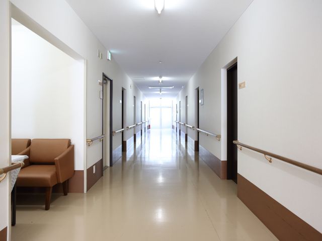 清潔感のある廊下 通路 やわらかい光が差し込む廊下は、安心感を与える落ち着いた色合いです。手すりが設置され、歩行に不安のある方も安心してお過ごしいただけます。