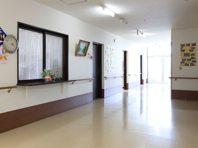 廊下に窓と掲示物 通路 ゆとりある廊下は見通し良好で、掲示物が彩りを添えています。手すりが整備され、移動の安全性に配慮されています。