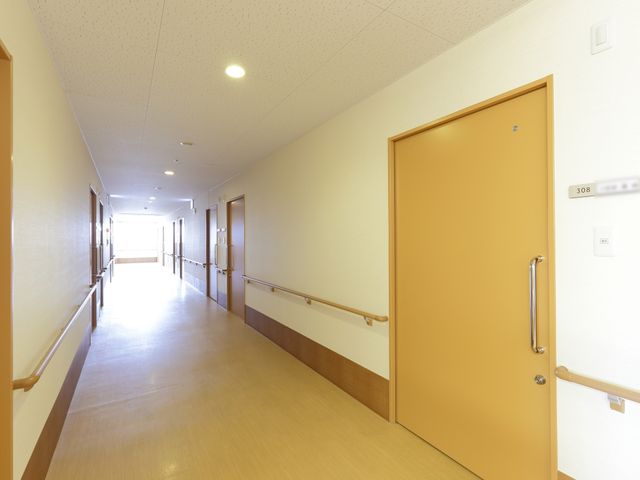 廊下の明るい手すりつき 通路 ゆったりとした廊下は、手すりが整備され安全に配慮された設計です。職員や利用者の方が快適に移動できる環境が整っています。