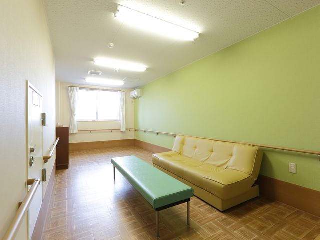 明るい居室の一角 共有スペース ゆったりとしたソファが配置された居室で、休息や訪問者との対話に適した環境です。安心して過ごせる明るい空間が整えられています。