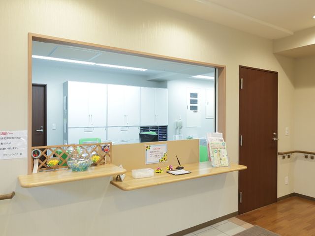 フロントのカウンターと背後の扉 受付 明るく清潔な受付カウンターが備えられたスペースです。ゆったりと待つことができる、落ち着いた雰囲気の場所です。