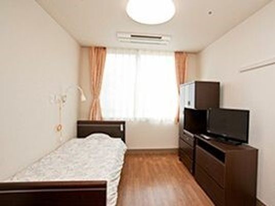 ベッドやタンス、テレビなどが置いてある一人用の部屋の写真
