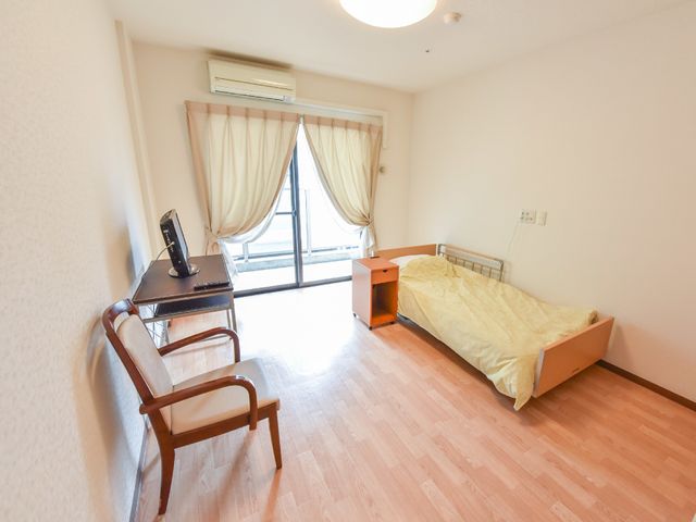 居心地の良い居室 個室 落ち着いた色合いの居室で、必要な家具が備わっており、快適な個人空間を提供しています。窓からは自然光が入り、温かみのある雰囲気が漂っています。