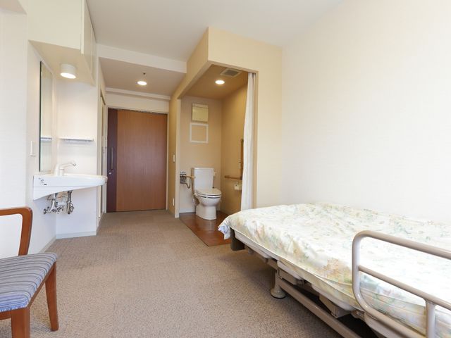 居室のベッドと洗面所 室内 清潔感のあふれる居室が整っており、快適な私空間を提供しています。個別の洗面台があり、日々の生活がより便利になっています。