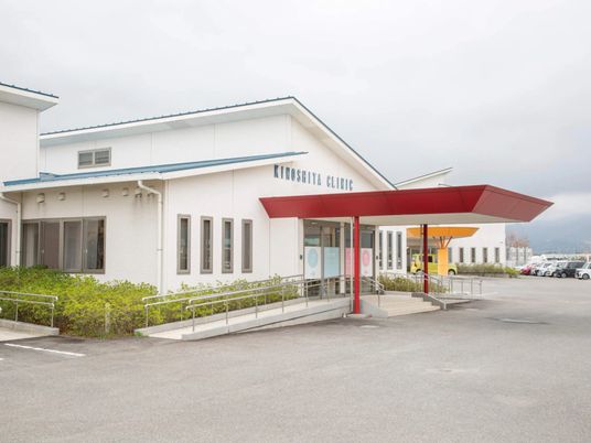 明るい外観と赤い庇の出入口  