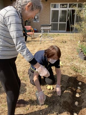 庭で植物の世話をする人達