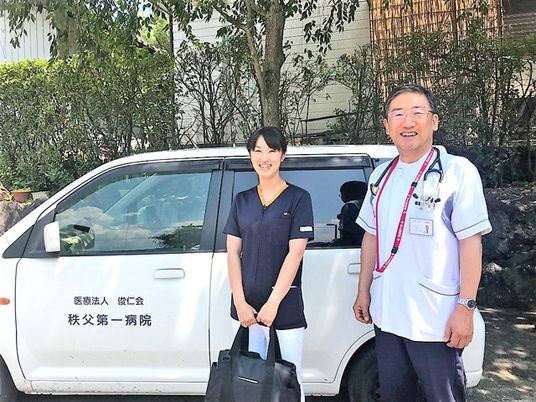 送迎車の前に立つ職員外観  