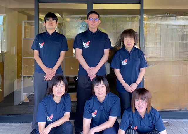 スタッフの集合写真 スタッフイメージ 笑顔で立つ職員さんたちが、温かい雰囲気を醸し出しており、訪れる皆さんを温かく迎え入れます。