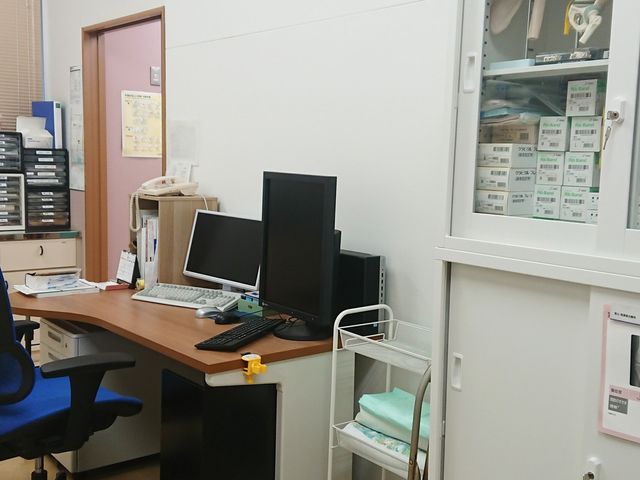 事務机と収納のある部屋 内観   事務作業用の机と複数のモニターが置かれた、落ち着いた空間です。収納棚や整理された備品から、日々の業務を支える様子が伝わります。