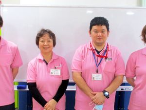 ピンク制服のスタッフとホワイトボードの前  