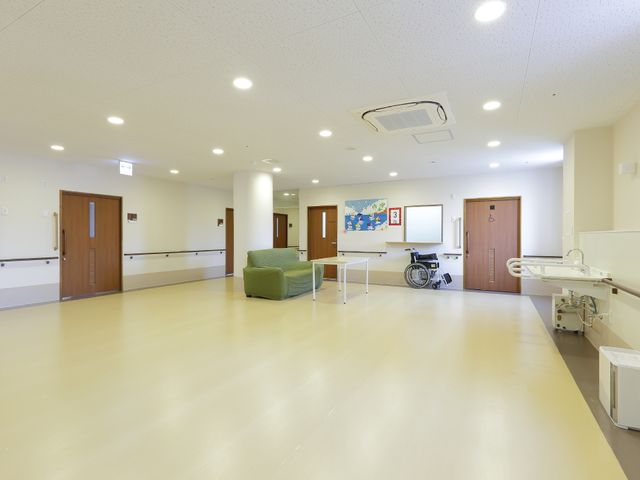 広々とした明るい廊下 居室前スペース ゆったりとした空間を持つこの廊下は、職員や利用者の方々が快適に移動できるよう工夫されています。車いすを置くスペースも確保され、利便性が考えられています。