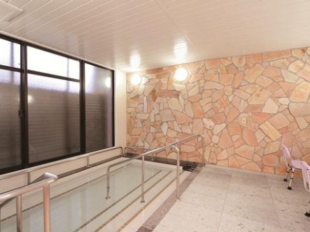 明るい入口廊下 浴室 ゆとりのある通路はさまざまな方々の移動を支え、壁面には温かみのある石の装飾が施されています。安全を考慮した手すりも完備しており、誰もが安心して過ごせる設計です。