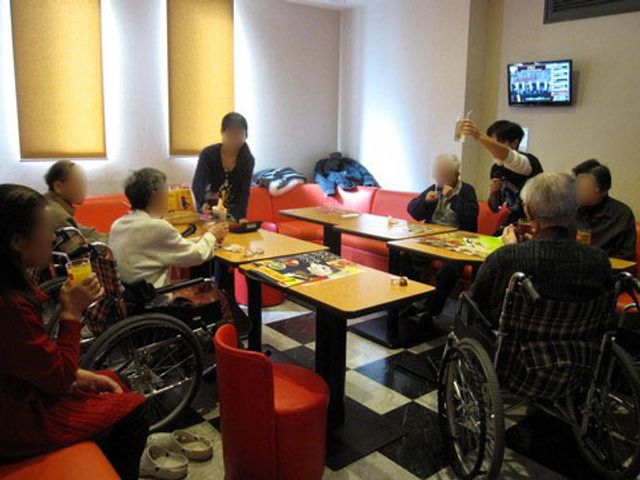 食事時の居心地の良い食堂 外出 赤い椅子が印象的な食堂で、入居者同士が楽しく食事をしています。車椅子に座った方もいらっしゃり、交流の場としても機能しています。