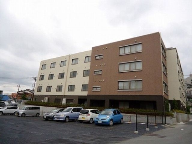 多階層の建物外観 施設外観 広々とした駐車場を備えた落ち着いた色合いの建物です。就業先として、安心感のある環境をご覧ください。