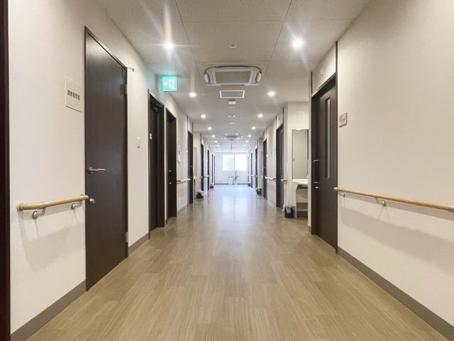長い廊下の風景 廊下 やわらかな照明と手すりが整った広い廊下です。清潔感があり、快適な移動をサポートします。
