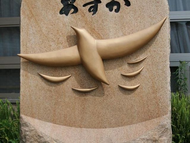 スズメの彫り物が施された石の看板 看板 入口に設えられた石の看板は、鳥のシルエットをあしらい、温もりを感じさせる歓迎の印となっています。