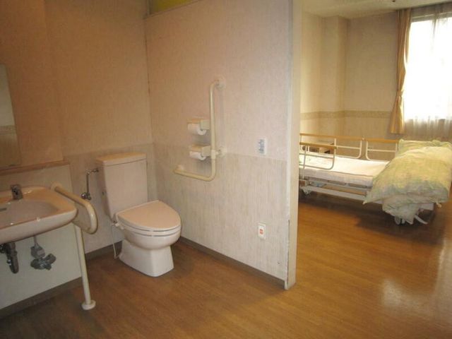 トイレ付き居室 居室   手すり付きのトイレと洗面台があり、居室から直接出入りできるつくりです。窓から自然光が入る、落ち着いた空間です。