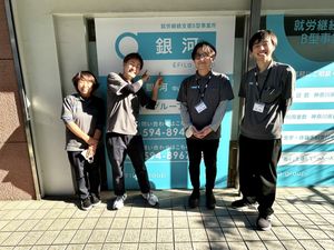 スタッフ4人と看板の前  