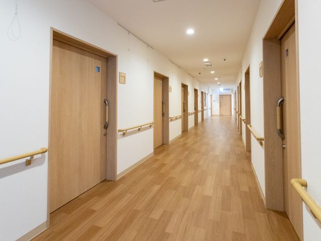 長い木目調の廊下 廊下 木目調の廊下は幅が広く、歩行補助用の手すりが両側に設置されています。車椅子でも通りやすい設計です。