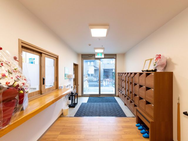 明るい玄関ホール エントランス   木目調の温かみがあるエントランスです。靴箱が整然と並び、出入口から外の様子も見えます。