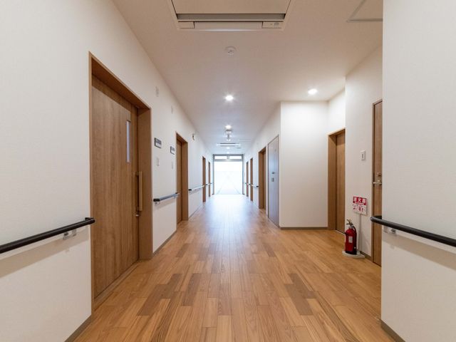 明るい廊下 廊下   木目調の床と白い壁で、すっきりとした廊下です。手すりが設置されており、移動しやすい環境が整っています。