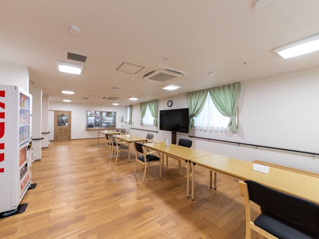 明るい食堂の様子 食堂   木目調の床とやわらかな照明で、落ち着いて過ごしやすい食堂です。窓際にはテレビもあり、休憩や交流の場として使いやすそうです。