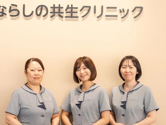笑顔のスタッフ3人と看板が見えるロビー  