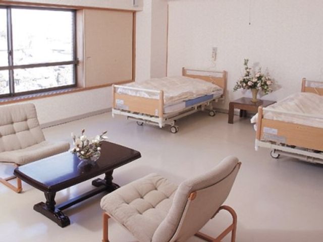 快適な雰囲気の居室 ２人部屋 窓から自然光が差し込む居室で、ゆったりとしたソファが配置され、心地よい休息が取れる空間です。ベッドもキャスター付きで動かしやすく、日常生活が快適に過ごせるよう工夫されています。