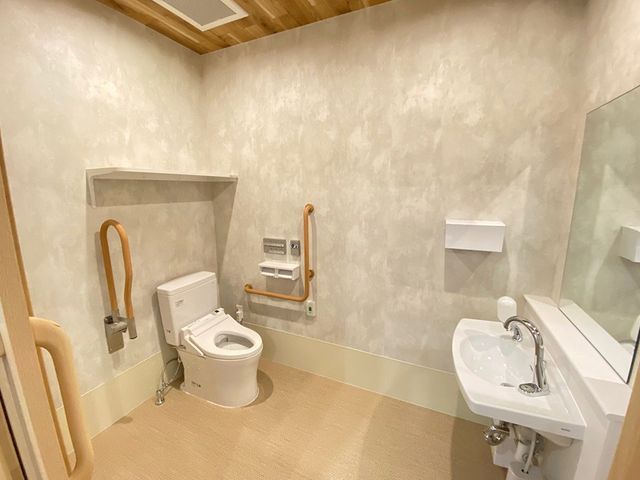 手すり付きのトイレ トイレ   広めの空間に手すりが設置され、動きやすさに配慮されたトイレです。洗面台もあり、介助や見守りのしやすさが伝わります。