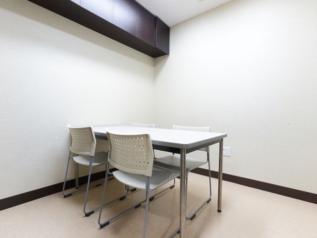 シンプルな居室の机と椅子 相談室 配置が整った居室の勉強スペースで、日々の業務準備を行います。心地よいプライベート空間での作業が可能です。