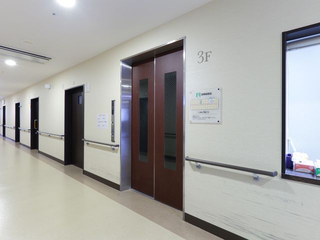 清潔感ある廊下の一角 エレベーター 広々として明るい廊下は、ゆったりとした移動ができる設計です。手すりが設けられ、安全に配慮された空間になっています。