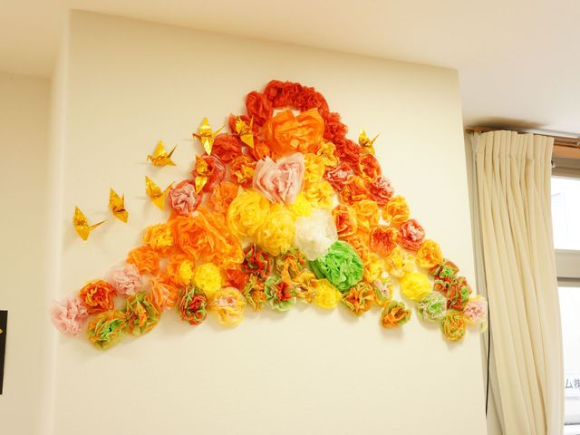 壁に飾られたカラフルな作品 リビングルーム 壁に飾られたカラフルな花と折り鶴は、明るい雰囲気を演出しており、身の回りに暖かさを感じさせます。ここでの暮らしに色と活気をもたらしてくれるでしょう。