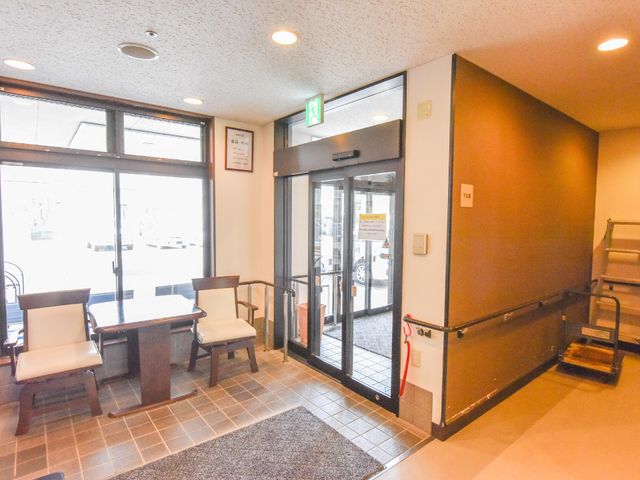 エントランスの待合室 玄関 入口近くの待合スペースです。座り心地の良い椅子とテーブルが配置され、明るい雰囲気でゲストをお迎えします。