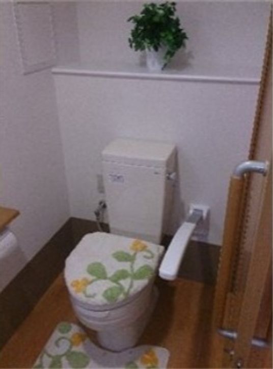清潔感のあるトイレの便器には布製のトイレカバーが設置されており、黄色の花柄でお洒落なデザインとなっている。