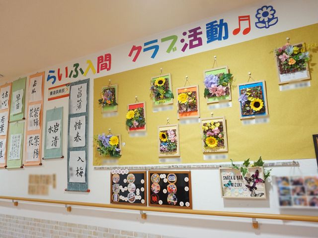 花と掲示物の廊下 展示物 廊下の壁には色鮮やかな花の飾りや様々な掲示物があり、温かみのある空間を演出しています。毎日の通り道が、ここにくる人々の心を豊かにしてくれるでしょう。