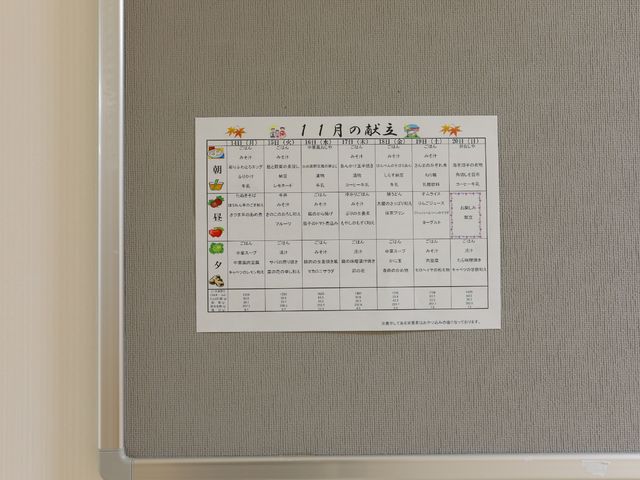 壁掛けのイベントカレンダー 展示物 明るい壁に月間スケジュールが掲示され、充実した日々のサポートが伝わります。