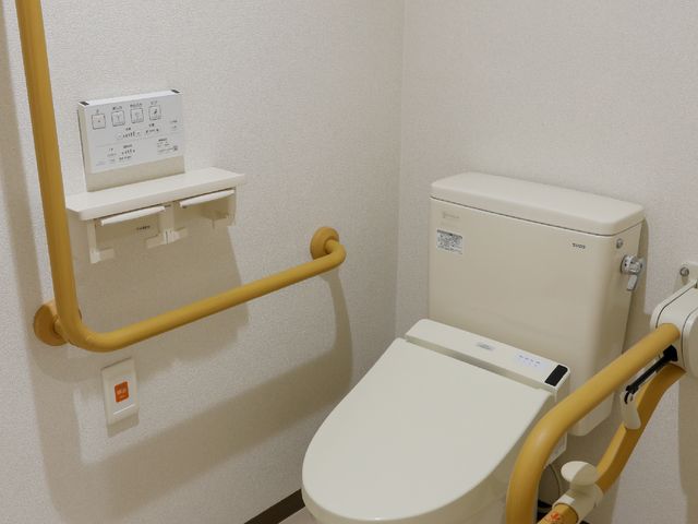 スロープ付き便座 トイレ 手すりが設置された安全なトイレ空間です。利便性と快適さへの配慮が見受けられます。