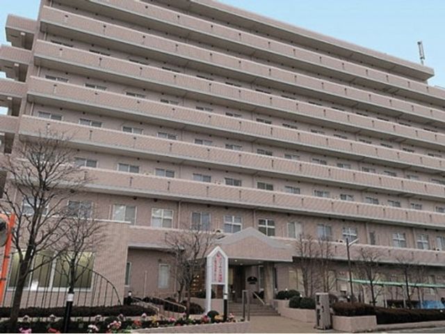 多階層の建物の正面 外観 多層構造で広々とした建物前は、整備された緑と花々で迎えてくれます。安心して勤務できる環境がここにあります。