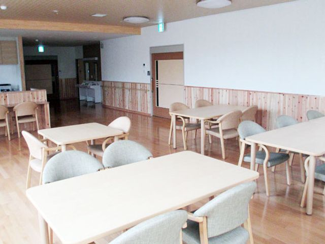 明るい居室の一角 居室 ゆったりとした空間の居室は、温もり感じる木のテーブルや椅子が配置され、安らぎを提供しています。