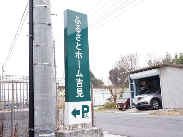 緑の案内看板 看板 目立つ緑色の案内看板が来訪者を迎え、分かりやすく駐車場への道案内をしています。