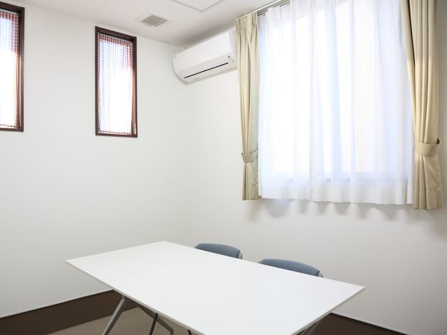 白い壁のシンプルな部屋 談話室 清潔感のあふれる空間で、日々の活動や休憩に適した多目的室です。エアコン完備で、快適な環境が保たれています。