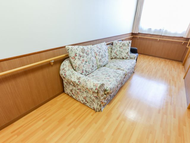 清潔な居室のソファ 廊下 広々とした空間に設置された柄ソファが、日の光を受けて温かみのある雰囲気を演出しています。ゆったりとくつろげる環境です。