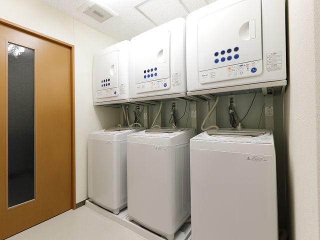 洗濯機と乾燥機が並ぶ部屋 自由に使える洗濯・乾燥機 清潔感あるランドリースペースは、日々の生活に便利を提供します。洗濯機と乾燥機が完備されており、利用者の快適な生活を支えています。