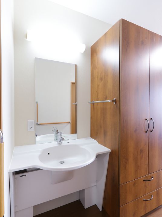 部屋の洗面台は白で統一されており、大きな鏡が取り付けられているので自分の姿を確認することができる。隣には大きなタンスが置かれている。